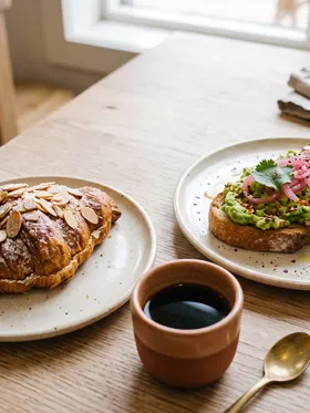 An almond croissant and a small plate of avocado toast